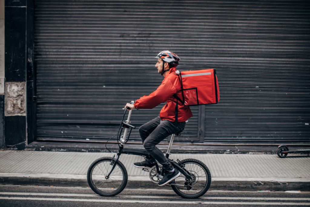 Boxed WARN class action settlement preliminarily approved. View of bicycle delivery person with food in a delivery backpack.