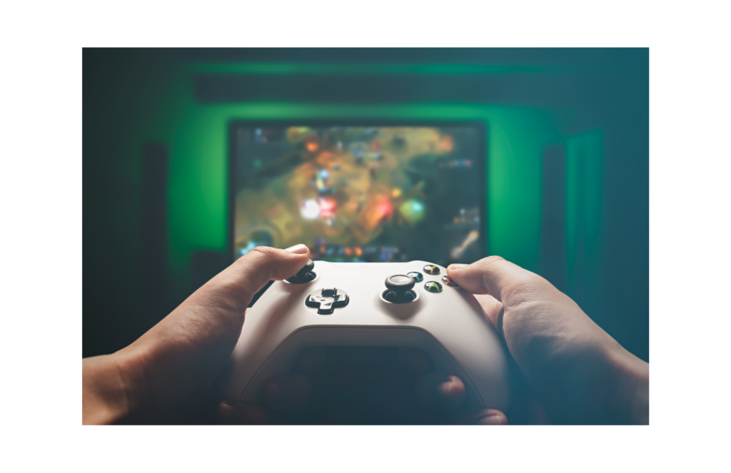 Intrepid Studios Class Action. View of gaming controller held by a gamer in foreground. In background, a computer game displayed on a big screen wall mounted TV.