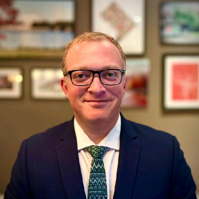 Headshot of Raisner Roupinian LLP partner Isaac Raisner. Wearing a blue sport coat with blue patterned tie.