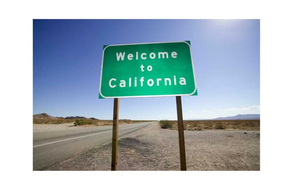 California WARN Act. View of a road sign reading California on a barren two lane highway with mountains in the distance.