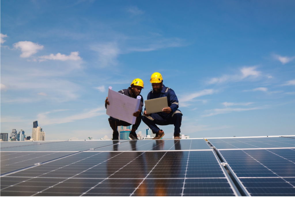 Allstate Sales Group layoff. View of two workers standing by a large solar panel. Both holding blueprints.
