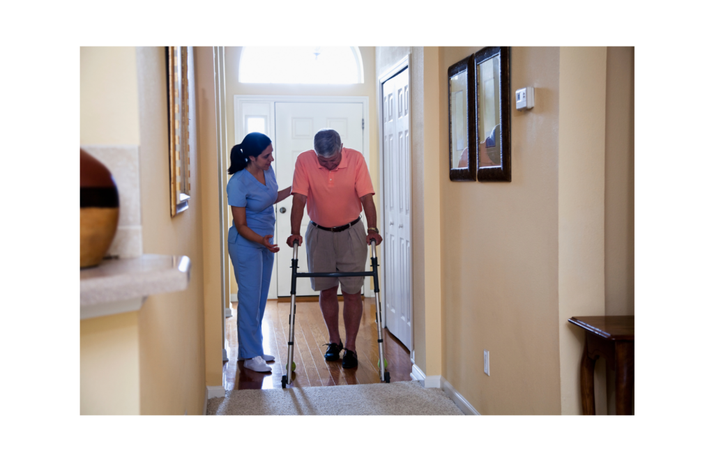 Anka WARN class action. Picture of a home health aide in blue scrubs helping a person in a pink polo shirt using a walker in a hallway.