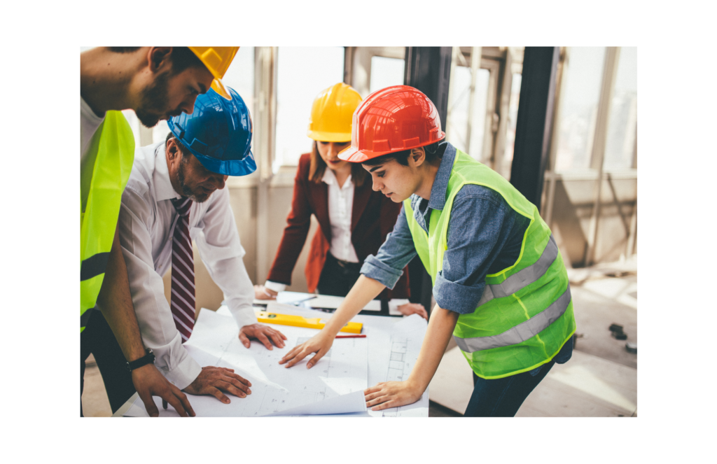 WARN class action settlement. Several male and female constructions workers reviewing blueprints in a partially finished building.
