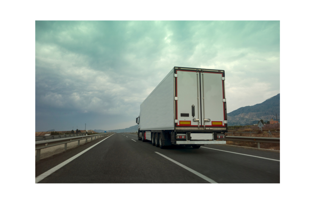 Yellow Trucking WARN class action. View of a white tractor trailer heading away from the camera on a two lane rural highway. Mountains shown in the background.