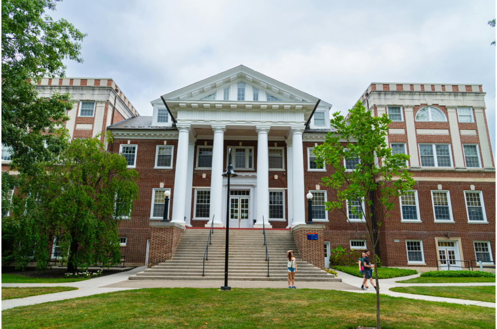 Dowling College WARN case. View of a red brick building with large white pillars on a college campus. This building has a large lawn with multiple sidewalks in front of it.