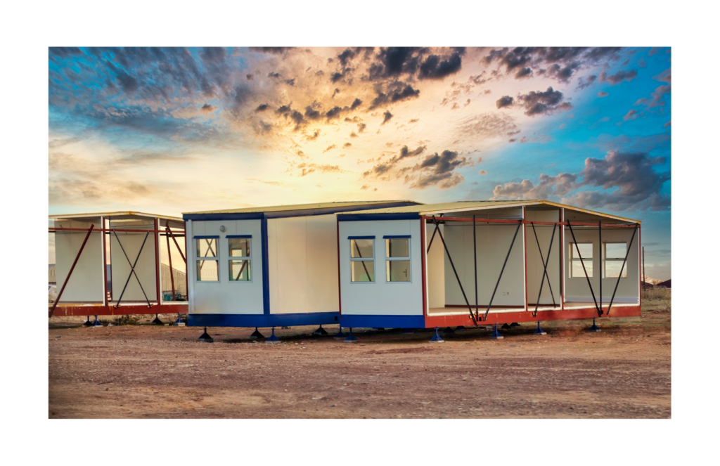 Innovative Building Systems WARN case. View of partially completed pre-fab houses. Shown is the left side of three houses in progress. They are resting on multiple jacks to keep them off the grounds. the partially built houses are blue and white or red and white.