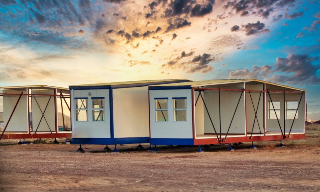 Innovative Building Systems WARN case. View of partially completed pre-fab houses. Shown is the left side of three houses in progress. They are resting on multiple jacks to keep them off the grounds. the partially built houses are blue and white or red and white.