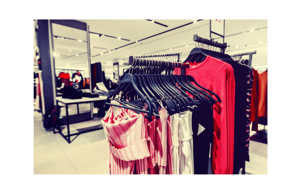 Shopko WARN class action. View of a small town department store. Dresses and women's clothes hanging on racks in a large space with mirrors, lights, and white walls.