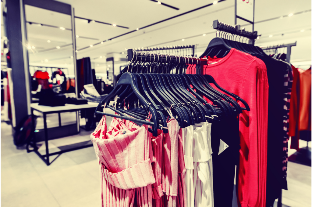 Shopko WARN class action. View of a small town department store. Dresses and women's clothes hanging on racks in a large space with mirrors, lights, and white walls.