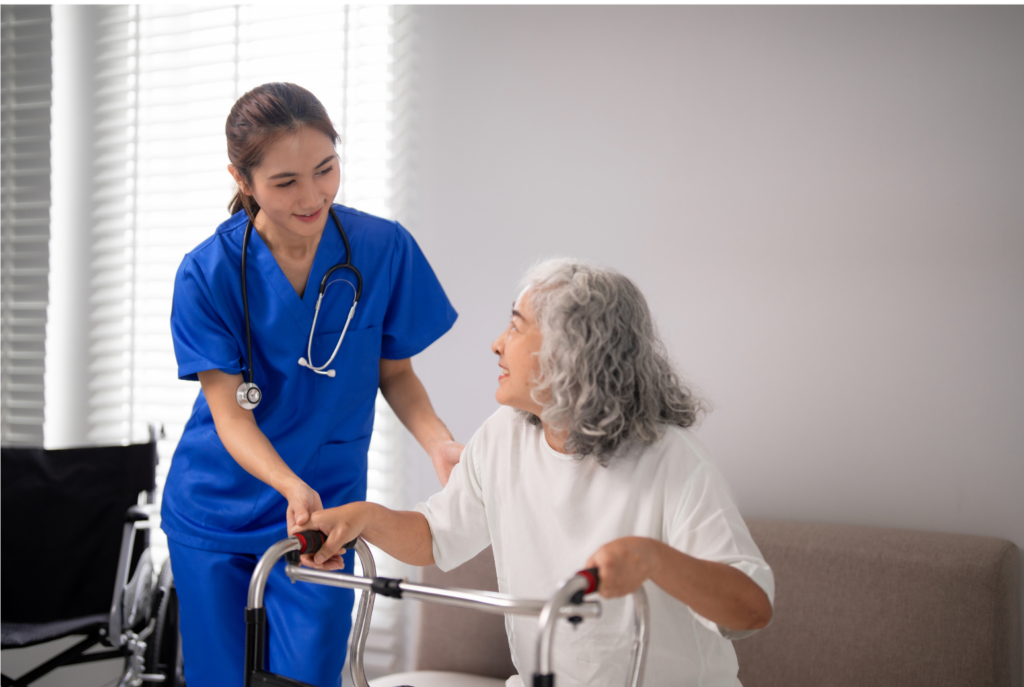 Univita Health WARN case. View of a woman home health aid in blue scrubs helping an older patient using a walker in white room.