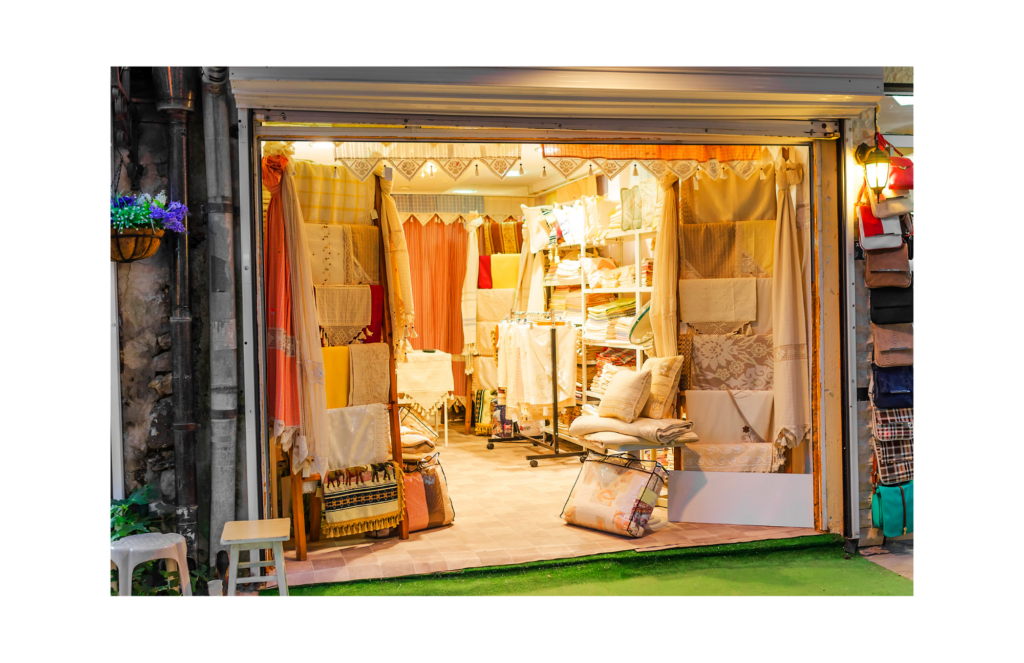 Anna's Linens WARN class action. View of a linen store with numerous items made of fabric on display, along with a number of satchels. There are dresses, sheets, table cloths, etc. of numerous colors--mostly white and pastels.