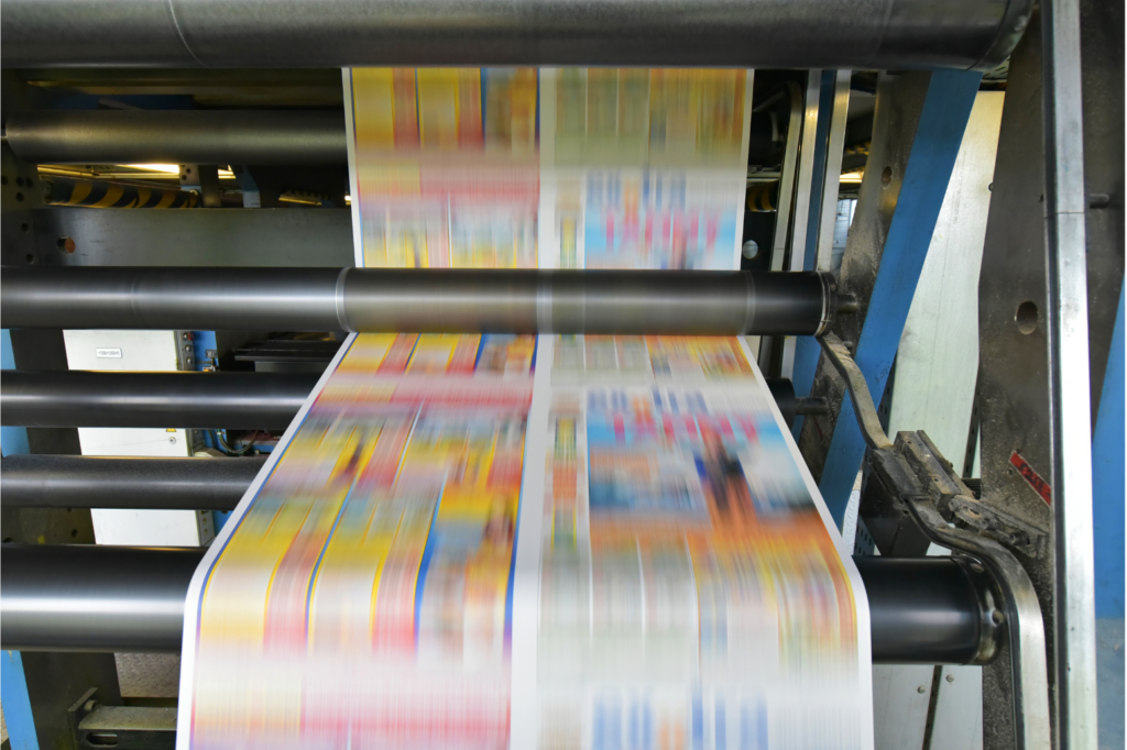 Colortree WARN class action. View of a high speed printing press with colorful printing shown on a long piece of paper as it moves through the rollers on the machine.