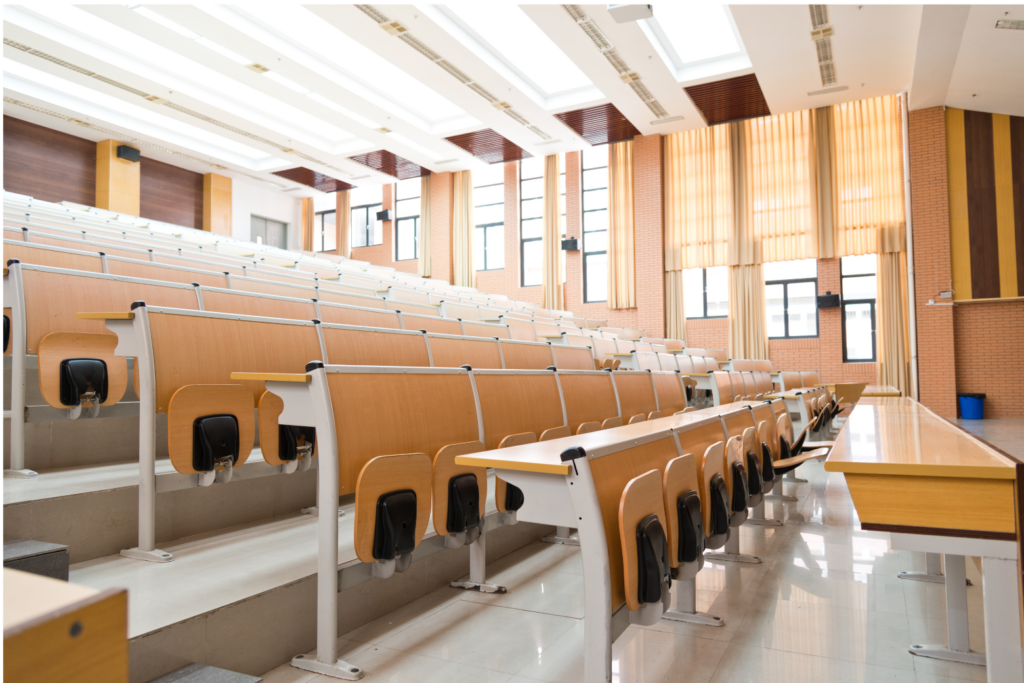 Corinthian Colleges WARN class action. View of a bright lecture room, empty of students There is tiered seating in the room with the furniture made of blonde wood with off white metal accents. The bottoms of the seats fold up when nobody is seated.