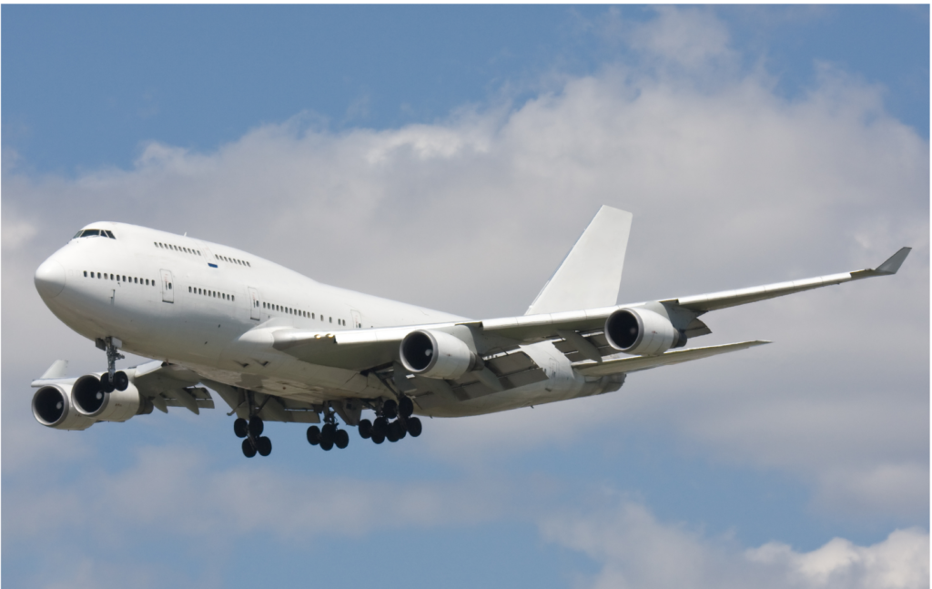 GDC Tecnics WARN class action. View of a Boeing 747 painted all in white with landing gear being either extended or retracted. The sky is a pale blue with wispy clouds in the background.