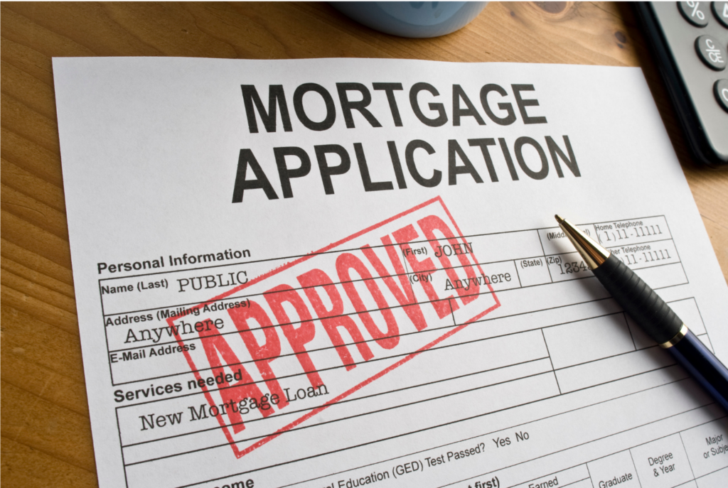 Ideal Mortgage/Lend American WARN class action. View of a completed mortgage application on a table with the word APPROVED stamped in red on it. On top of the application is a pen. Beside the pen there is a partial view of left side of a desk calculator.