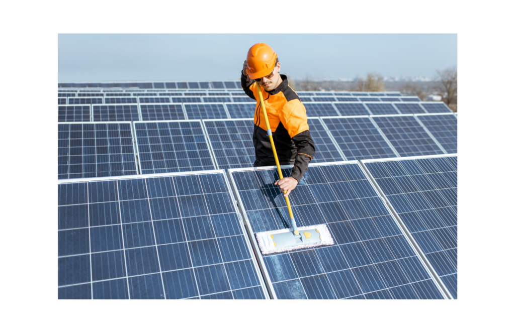 Meyer Burger WARN class action. View of a worker in orange and black and with a black hard hat using a swiffer type mop to clean solar panels. He is standing amidst an entire field of solar panels.