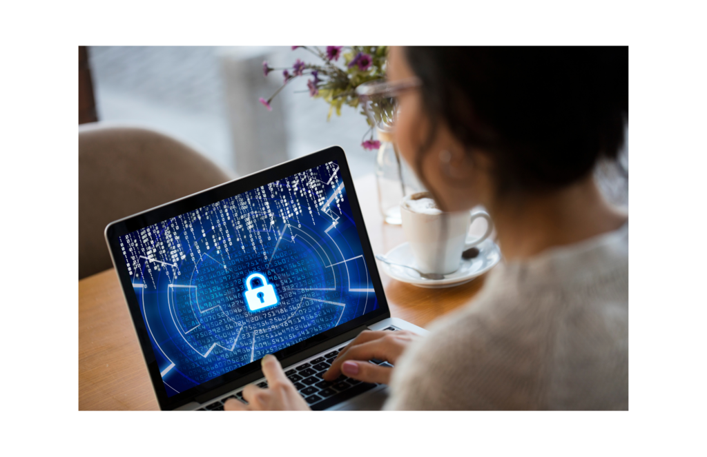 NS8 WARN class action. A woman with glasses using a laptop at her desk. Flowers and a cup and saucer are on the desk. The laptop displays a centered padlock icon with a grid of random numerals displayed in white against a blue background.