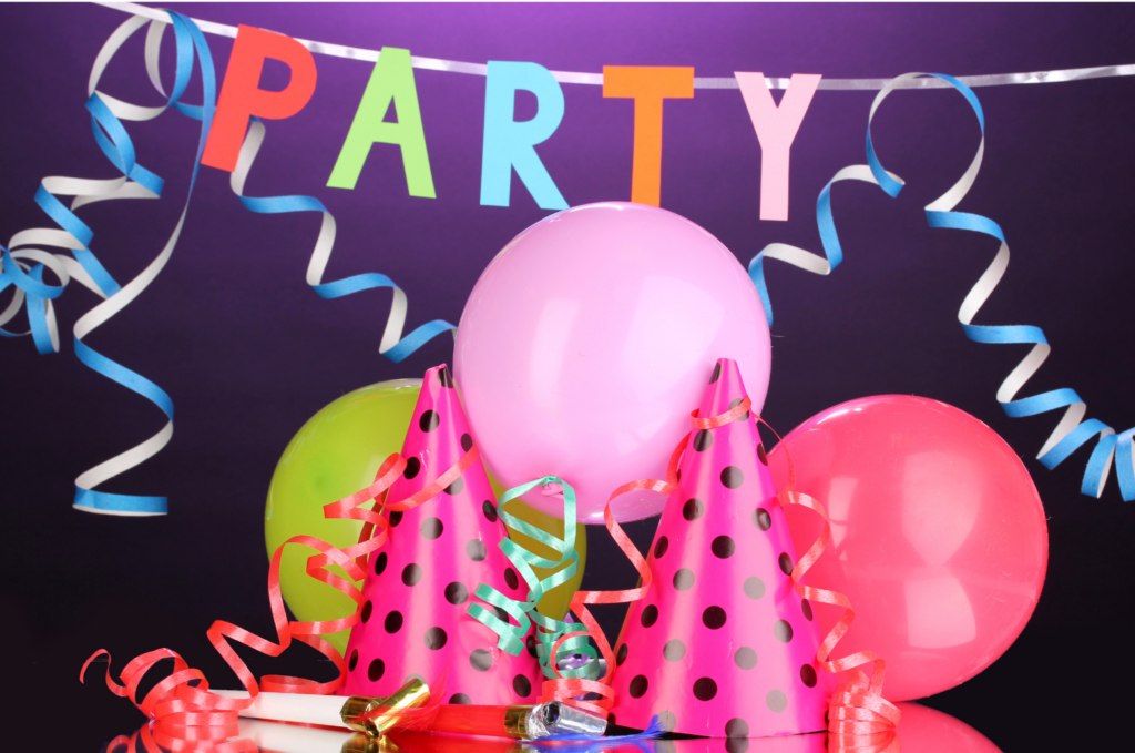 Party City WARN class action. View of a purple wall with a letters strung from the walls reading P-A-R-T-Y. Ballons, horns, and party hats in the foreground.
