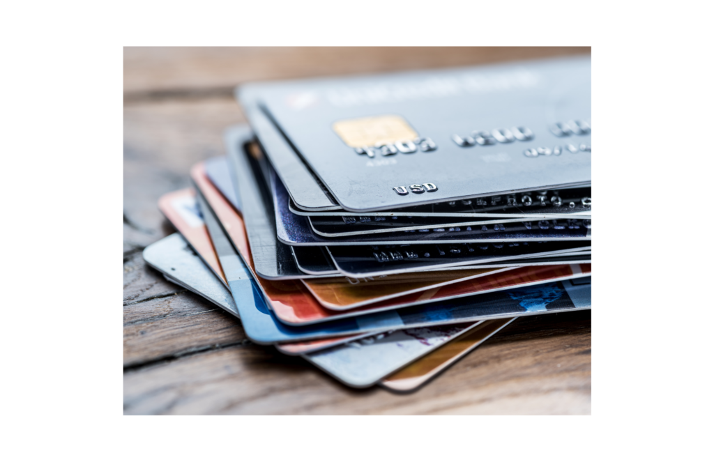 Progrexion WARN class action. Close up view of a blurry stack of about 15 credit cards slightly spread out on a wooden table.