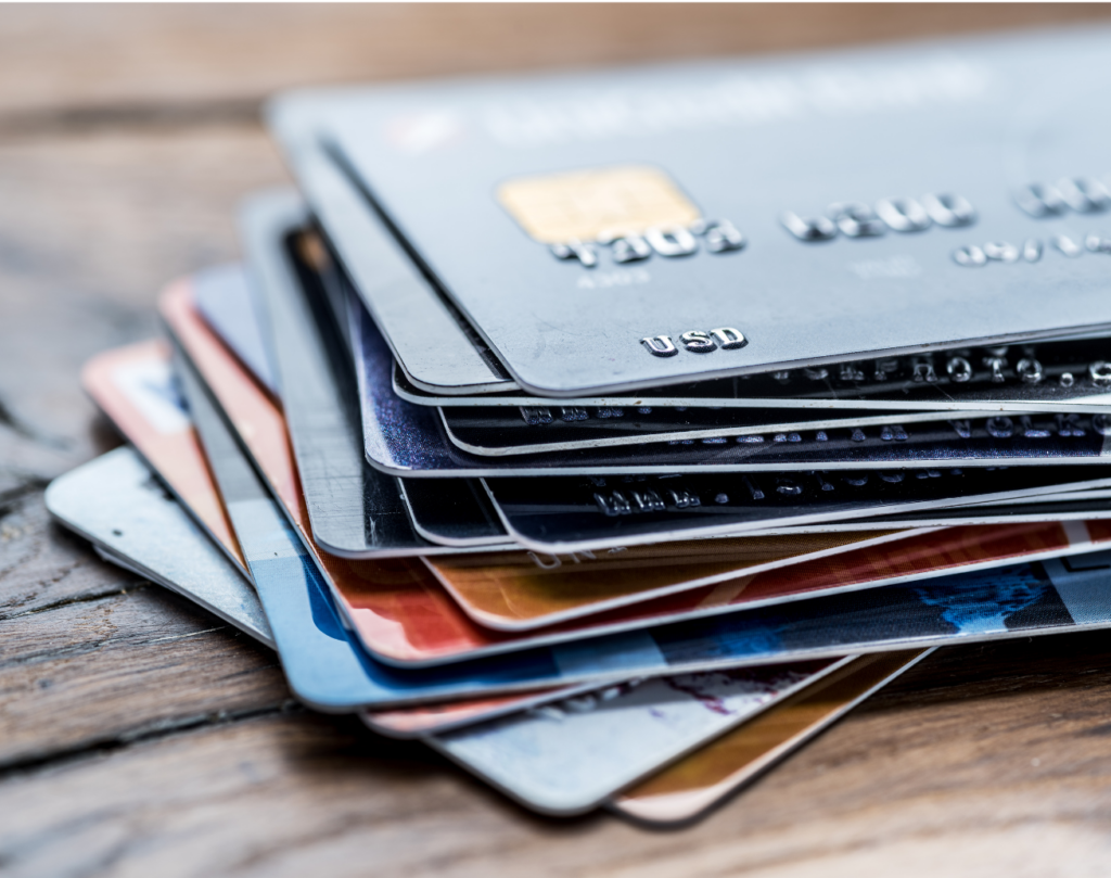 Progrexion WARN class action. Close up view of a blurry stack of about 15 credit cards slightly spread out on a wooden table.