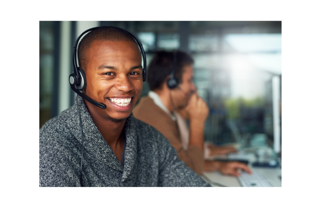Results CSX WARN class action. Close up view of person in a telephone headset smiling at the camera. A co-worker in the call center is in the background.