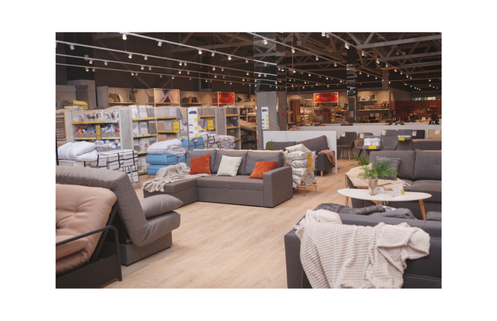 Tuesday Morning WARN class action. View of a moderately priced furniture store showroom. Couches with decorative throw pillows and coffee table, with shelves of other products for sale in the background.