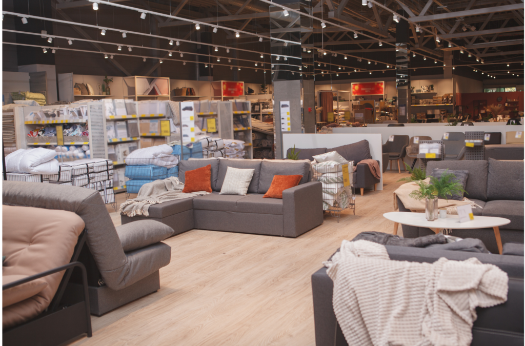 Tuesday Morning WARN class action. View of a moderately priced furniture store showroom. Couches with decorative throw pillows and coffee table, with shelves of other products for sale in the background.